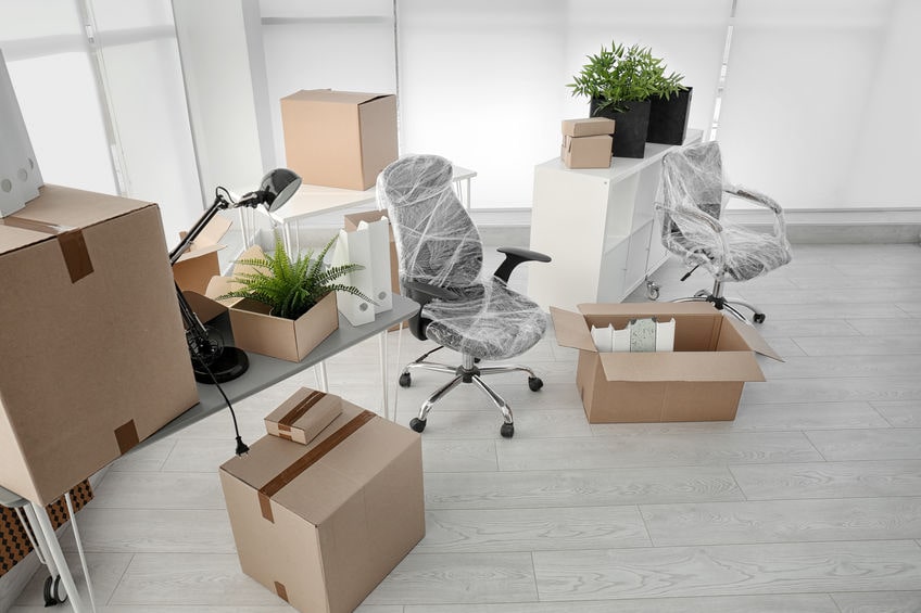 Office furniture and boxes packed for relocation, highlighting the cost and hassle compared to serviced offices in Singapore.