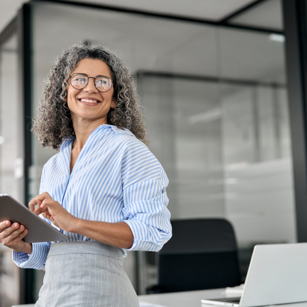 Smiling businesswoman using a tablet in a modern serviced office in Singapore, representing cost-effective serviced offices for rent for SMEs
