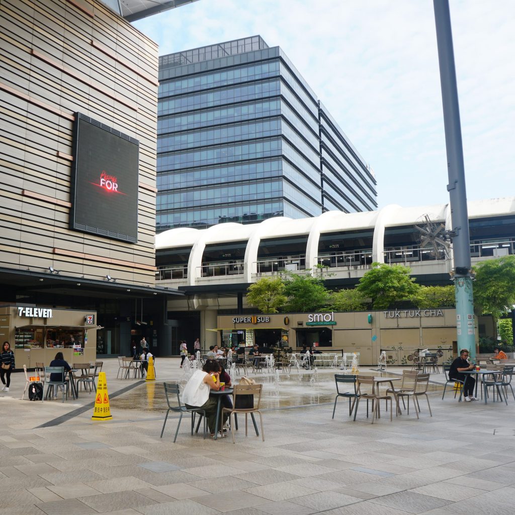 a plaza with chair and tables in front of Paya Lebar Square and other office buildings in Singapore