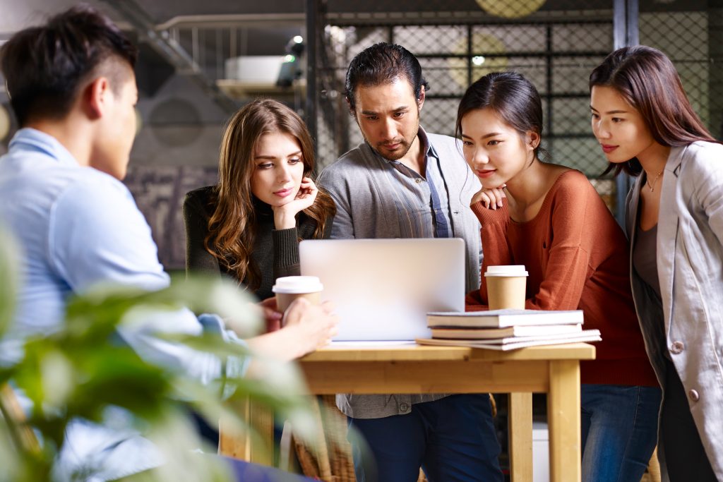 employees gathered at a laptop, working at an office rental in Singapore