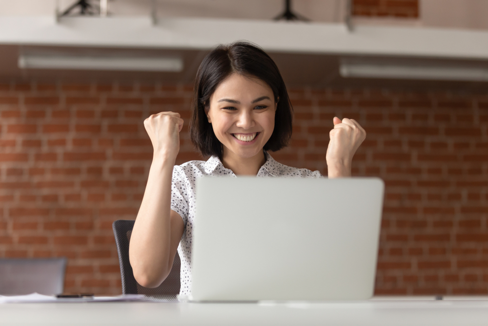 Lady pumping her fists after receiving correspondence on the company's winning bid on a corporate bidding process. A virtual office solution in Singapore helps foreign companies participate in local tenders and corporate deals.