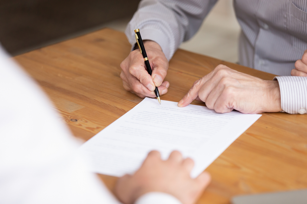 Employee writing on the bottom of the paper with a fountain pen, indicating a contract signing with a virtual office to rent