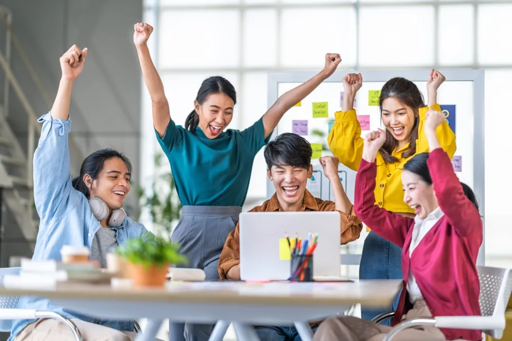 Cheering employees, indicative of an engaging and efficient work setup brought about by a virtual office space in singapore
