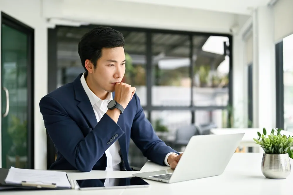 A man pensively working on his laptop as part of a virtual office setup in Singapore