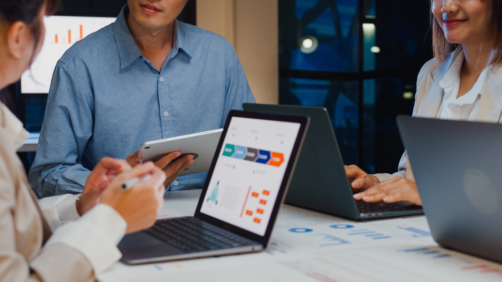 A department holding a strategy meeting and brainstorming ideas, laptops are on the table. A company using a virtual office space in Singapore must encourage innovation through feedback.