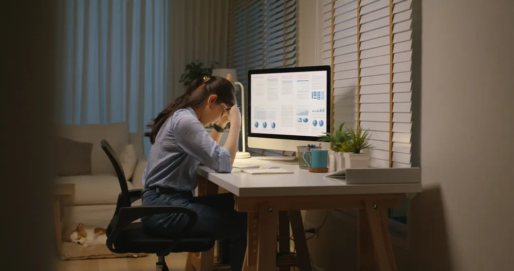 A lady having a migraine in front of a computer after assessing the pitfalls associated with the wrong virtual office in Singapore